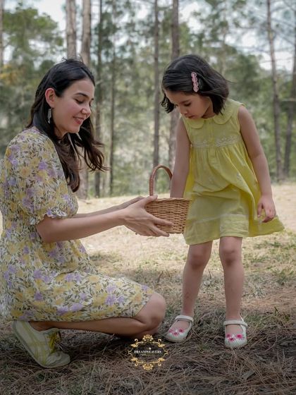 A mother and daughter interact with a small basket during a picnic-themed shoot in the woods.