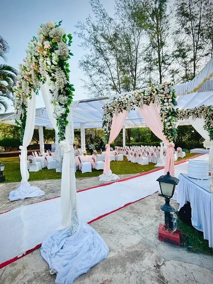 A wide view of a beautiful daytime wedding setup, with floral arches creating a picturesque pathway for the couple's entrance.
