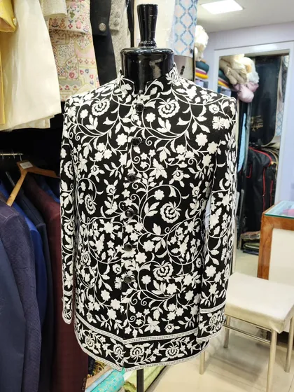 Inspired by celebrity style, this black Jodhpuri jacket features a bold white floral print. It's a fashionable choice for anyone looking to make a statement at a wedding.