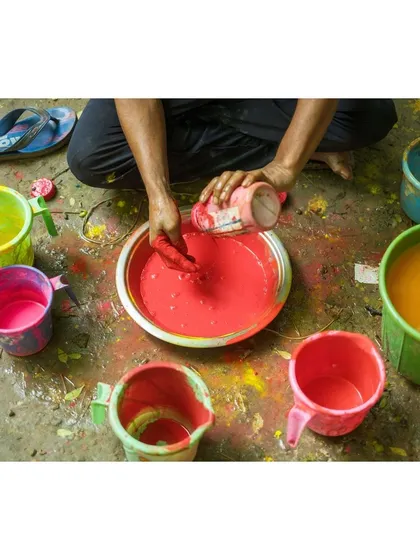 A craftsman mixes vibrant red paint, a color central to the iconography of the Durga Puja festival.