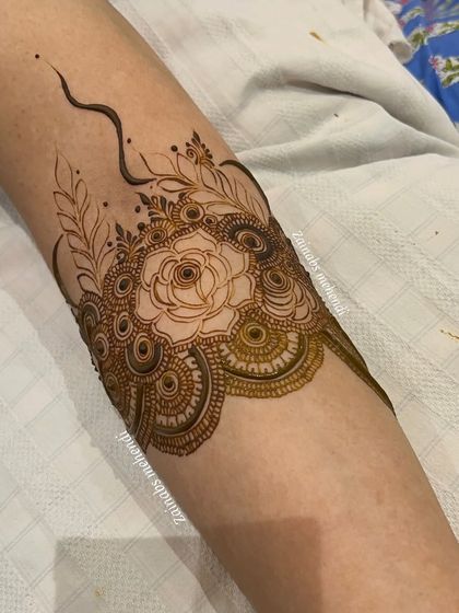 Another angle of Nida's armband, showing the fine lines and delicate leaves surrounding the central rose.