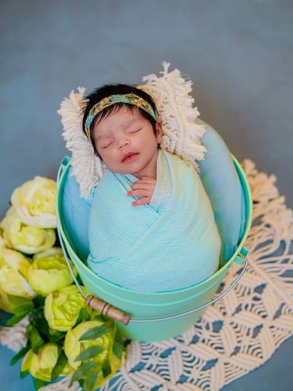 A bucket of sweetness. I use props like this little bucket to safely pose swaddled babies, creating a charming and rustic look.