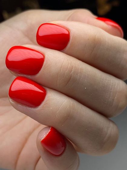 A classic, vibrant red manicure on short, squared-off nails. The high-gloss finish makes this timeless color pop.