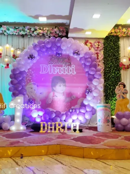 A magical Disney Princess theme for a first birthday party. This grand stage setup features a circular balloon arch, cutouts of princesses like Elsa, Ariel, and Belle, and a personalized backdrop for the birthday girl.