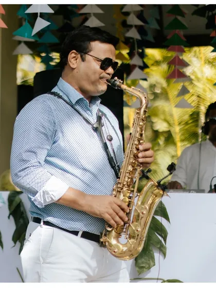 A live saxophonist playing by the pool, setting a cool, relaxed, and sophisticated vibe for a daytime party.