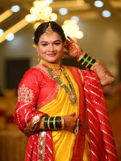A confident and happy bride in her yellow and red wedding saree. The makeup is bold yet traditional, perfect for a grand celebration.