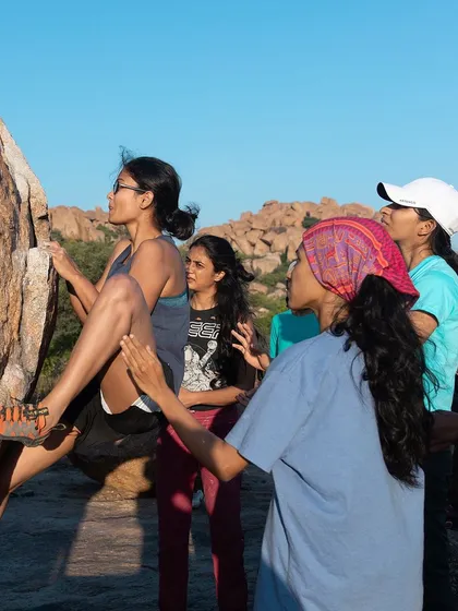 Climbing is focus. Here, a climber studies the rock, while her community watches and supports her.