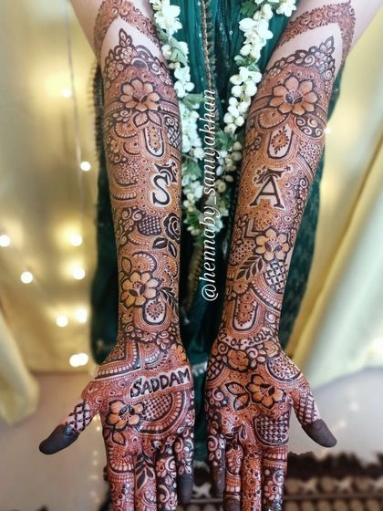 The bride proudly displaying her mehendi, with the initials 'S' and 'A' and the name 'Saddam' clearly visible.
