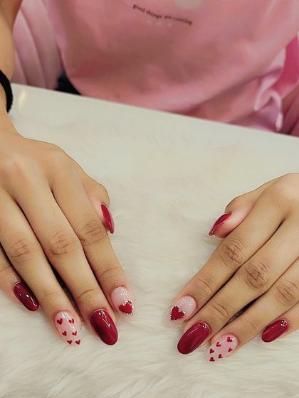 Let your nails express the love. This Valentine's set features a mix of solid red nails and accent nails with a sheer base and tiny red hearts.