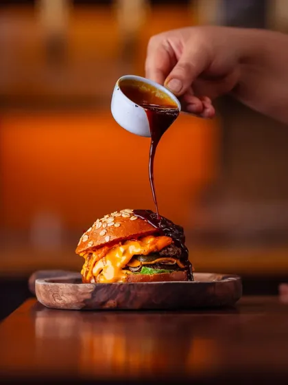 Desire takes shape in my crafthouse. This is our Classic Beef Smashed Onion Burger, where a perfectly seared patty meets cheddar cheese and chargrilled onions, all drenched in our signature sauce. It’s a moment of pure, unadulterated pleasure.
