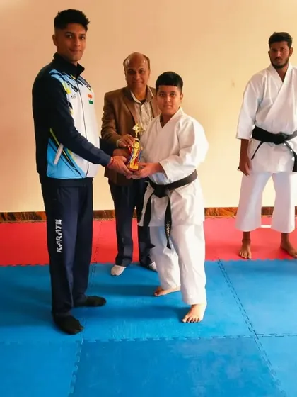 A young student receives his trophy after successfully achieving his black belt. A proud moment for him and the academy.