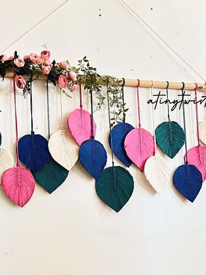 For a bolder look, this leaf wall hanging combines vibrant pinks and deep blues with natural white. The floral accents add an extra touch of elegance.