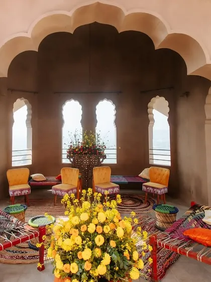 A traditional seating area with 'charpai' beds and colorful decor inside an arched alcove. This space offered guests a comfortable and authentic spot to relax during the Haldi festivities.