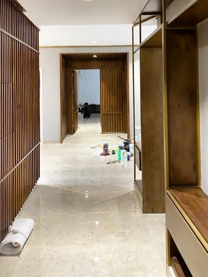 A work-in-progress view of the Gurgaon residence corridor, showcasing the stained pine wood panels with brass inlay details before the final finishing touches.