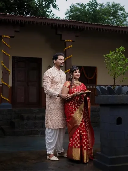 The couple stands by a Tulsi plant in a traditional courtyard, a serene moment from their pre-wedding shoot.