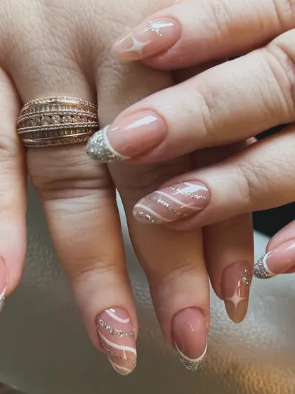 A sophisticated French manicure with a sparkling silver glitter tip, accented with swirls and starburst designs.