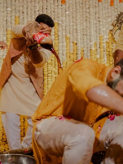 The groom getting drenched during his Haldi ceremony, a classic moment of celebration.