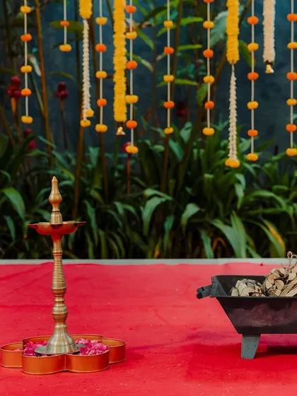 Simple details can create a powerful atmosphere. A traditional brass lamp, or 'diya', placed on a bed of flower petals adds a warm and sacred glow to any Indian wedding ceremony.