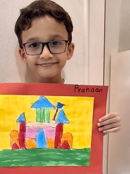 A young artist proudly holds his completed castle artwork. The smile on his face shows the confidence gained from mastering a new drawing.