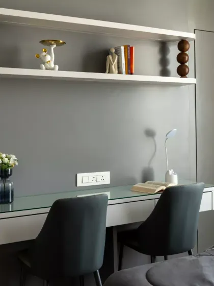 A refined study nook designed for focus and creativity. The sleek desk with a glass top enhances openness, while the sculptural shelving, adorned with wooden sphere accents, adds a playful yet sophisticated rhythm to the design.