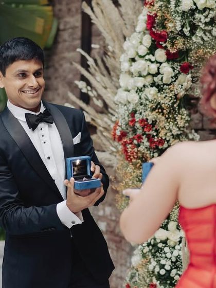 The groom's joyful reaction as he proposes to his bride during their engagement party. A moment of pure, unscripted happiness.