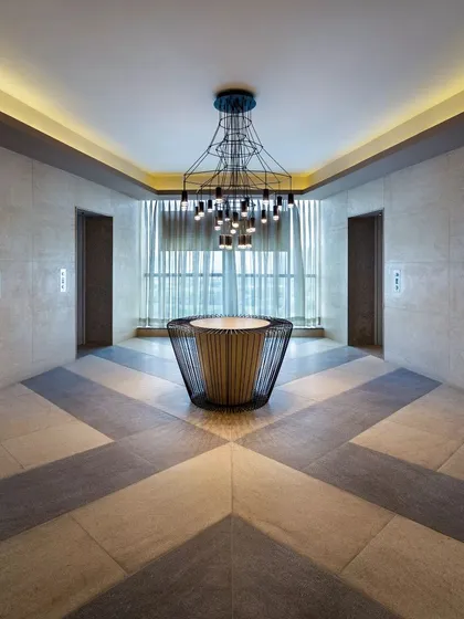 The elevator lobby at Conscient One features a striking geometric floor pattern and a central sculptural light fixture. The design turns a transitional space into a memorable design moment.