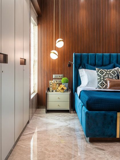 A bold and elegant bedroom design. The deep turquoise velvet bed stands out beautifully against the wooden fluted wall panel, creating a rich and luxurious atmosphere.