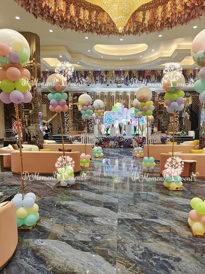 A view of the entire hall decorated with a hot air balloon theme. Tall balloon arrangements line the main walkway, leading guests' eyes towards the main stage and creating a cohesive and immersive environment.