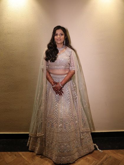 A beautiful full-length portrait of Urvashi, ready for her engagement party. The soft makeup and hairstyle perfectly complement her stunning, shimmery lehenga.