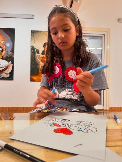 A student carefully selects her colors, thinking through her creative choices for her drawing of the characters Stitch and Angel.