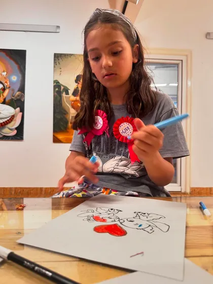 A student carefully selects her colors, thinking through her creative choices for her drawing of the characters Stitch and Angel.