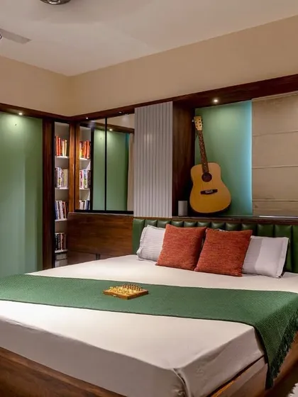 This bedroom features a dark wood bed with a green leather headboard and a custom niche for a guitar, reflecting the occupant's personality and hobbies.