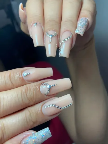 This set of long, nude acrylic nails is decorated with intricate, flowing lines of rhinestones for a glamorous and sophisticated look.