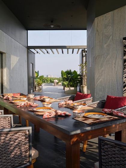 Another view of the terrace dining setup, showcasing the use of natural materials and colorful textiles to create a warm and inviting atmosphere.
