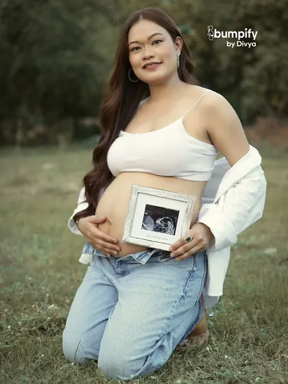 A full portrait of the mom-to-be in her casual jeans and crop top outfit, proudly holding her sonogram picture. This shows that you can be comfortable and stylish for your shoot.