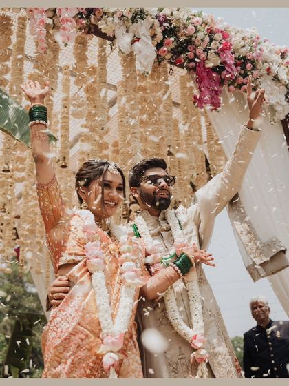 Pure celebration! The couple cheers under a shower of kaleeras, their joy lighting up the frame.