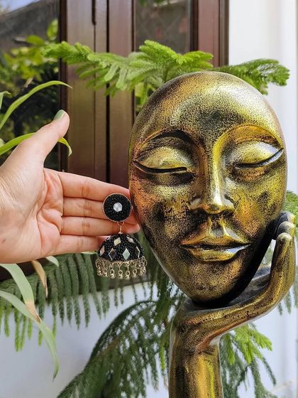 A slightly different angle of the black oxidised mirror work jhumka, showing its dome shape and delicate ghungroo details.