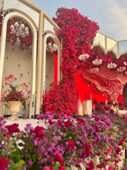 A view of the stage from the side, where mirrored arches are framed by a profusion of red and purple flowers, creating a scene of opulent drama.