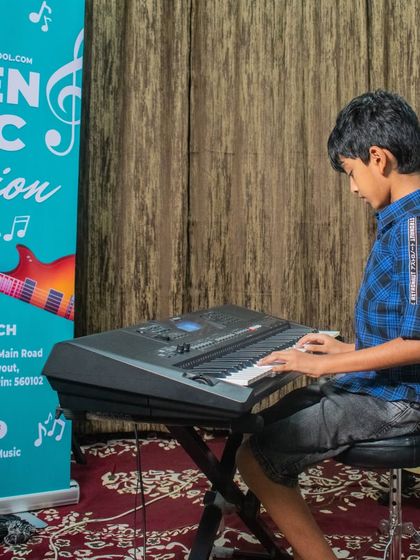 A student plays the keyboard at the HSR branch open mic, with our banner in the background.