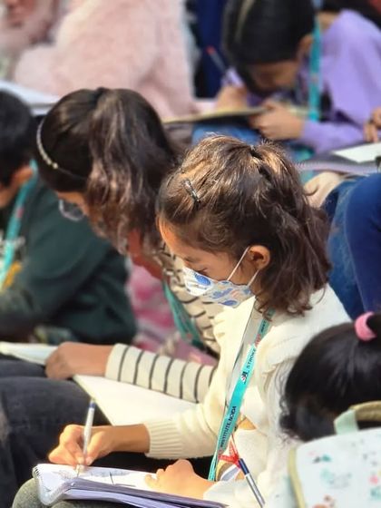 A close-up of young students sketching in their notepads during our outdoor class, capturing the world around them.