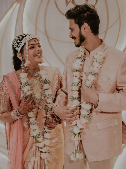 A candid, joyful moment between the couple, with their beautiful floral varmalas.