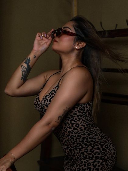 A dynamic shot with hair in motion as the model adjusts her sunglasses, adding energy to the photo.