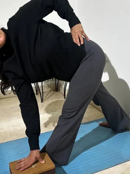 This student uses a wall and block for a supported Triangle Pose. This Iyengar-inspired approach ensures stability, allowing for a deeper and safer expression of the asana.