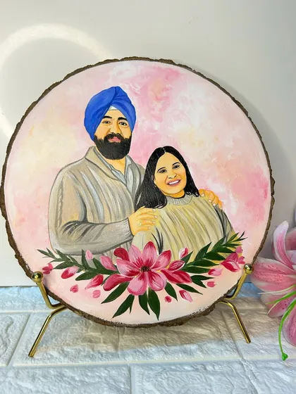 A close-up of a finished couple portrait on a wood slice, displayed on a classy golden stand. The soft pink tones and floral details make it a beautiful decorative piece.
