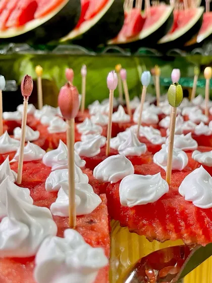Watermelon cubes topped with whipped cream and decorative picks. This simple, creative presentation makes a common fruit feel special and fun.