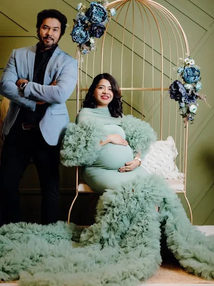 A stylish couple's shot in the studio. The mint green maternity gown provides a soft, beautiful color palette against the olive green wall and floral props.