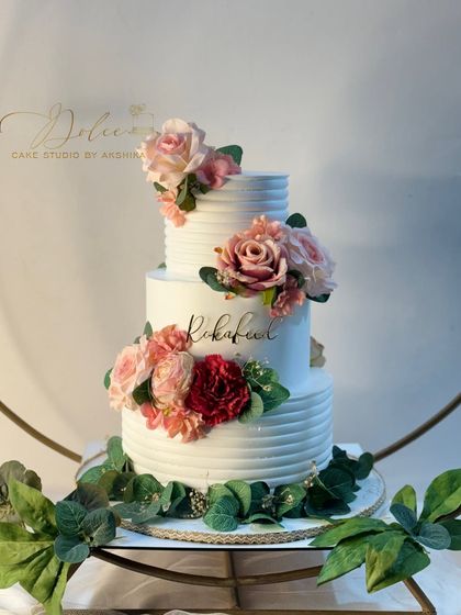 A closer look at our rustic floral wedding cake. The combination of the textured buttercream and the arrangement of pink and red roses creates a romantic and timeless look.