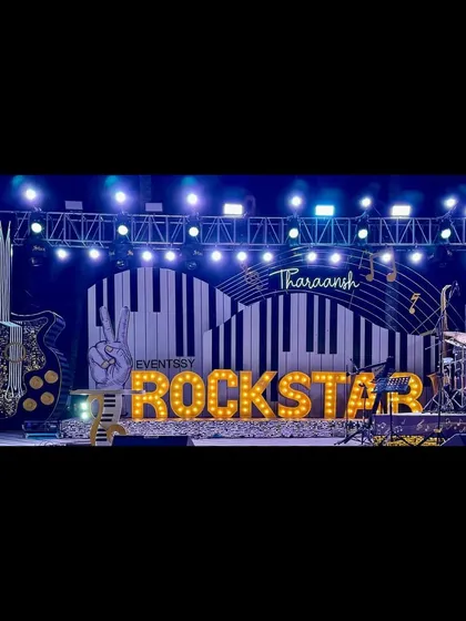 A panoramic view of the epic Rockstar stage at night, complete with a drum kit, giant guitar prop, and professional lighting rig.