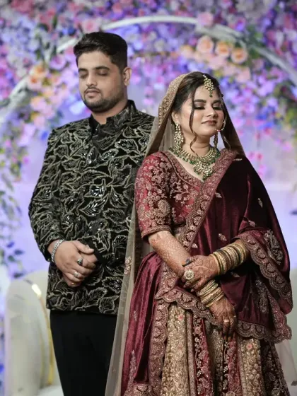 A formal portrait of the bride and groom during their wedding reception, set against a beautiful floral and candlelit backdrop.