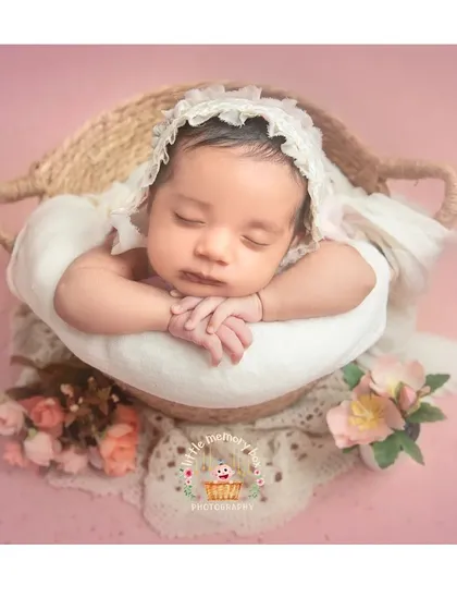 A classic basket pose with a vintage feel. The lace bonnet and soft floral accents add a timeless and delicate touch to this newborn portrait.